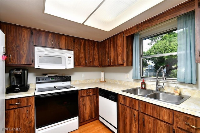 kitchen featuring white appliances, light countertops, a sink, and light wood finished floors