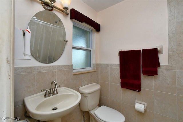 bathroom with wainscoting, a sink, tile walls, and toilet