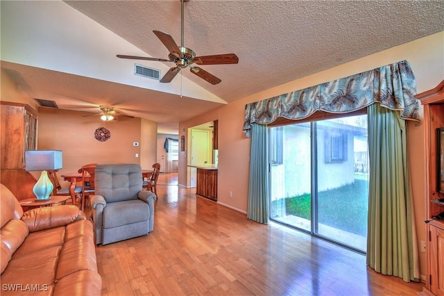 living area with lofted ceiling, a healthy amount of sunlight, and visible vents