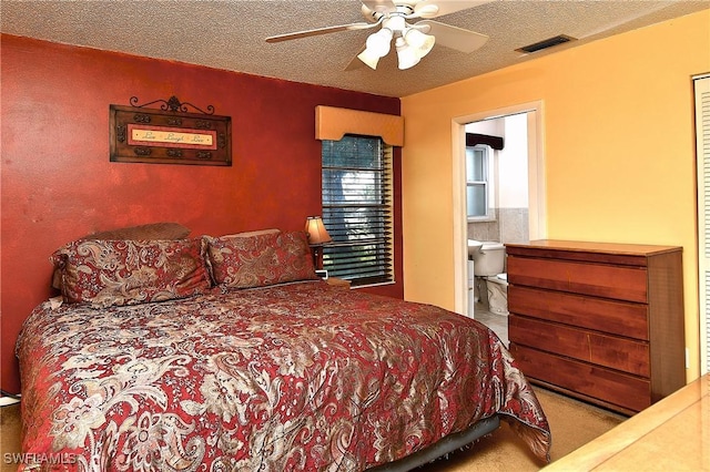 bedroom featuring visible vents, a ceiling fan, ensuite bathroom, carpet, and a textured ceiling