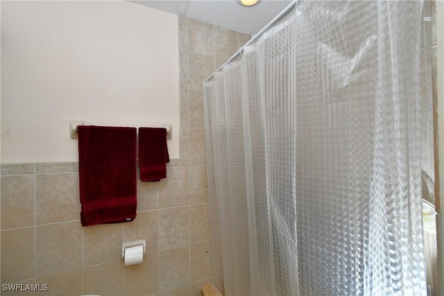 bathroom with a stall shower and tile walls