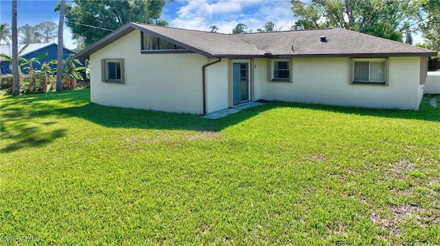 back of property featuring stucco siding and a yard