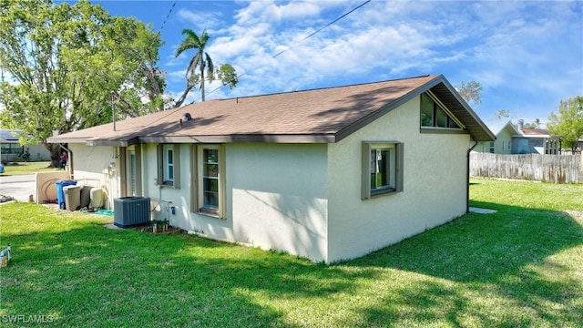 back of house featuring a lawn, stucco siding, fence, and central air condition unit