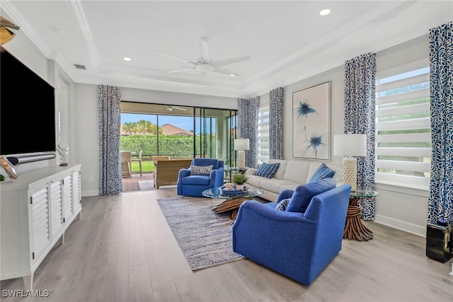 living area featuring baseboards, a raised ceiling, visible vents, and light wood-style floors