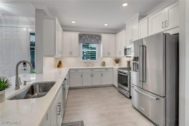 kitchen with a sink, white cabinetry, ornamental molding, appliances with stainless steel finishes, and decorative backsplash