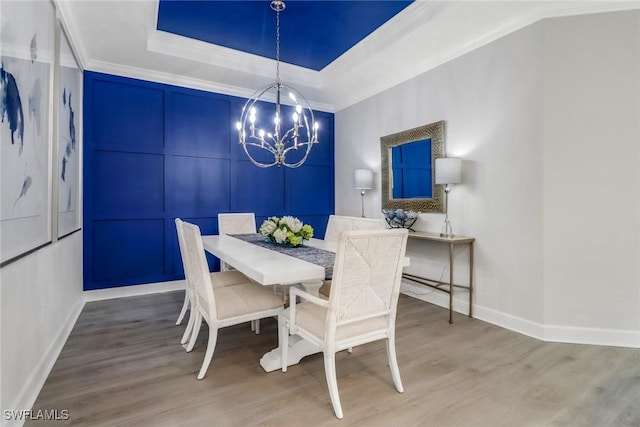 dining space featuring a chandelier, a tray ceiling, crown molding, and wood finished floors