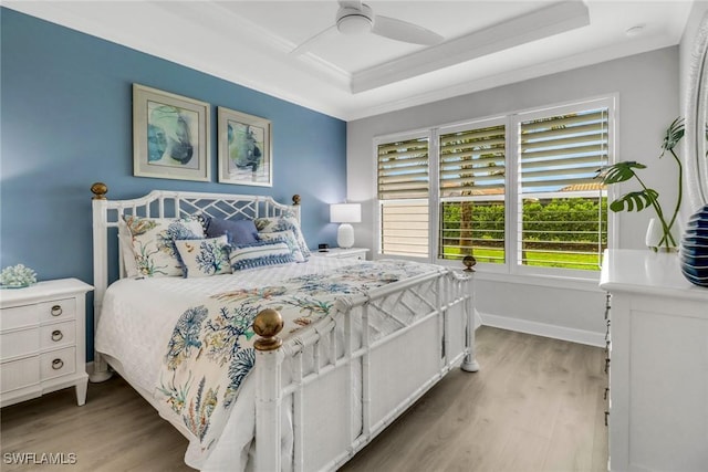 bedroom with baseboards, crown molding, and light wood finished floors