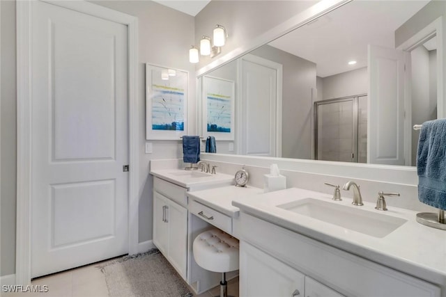 full bath featuring double vanity, a stall shower, tile patterned flooring, and a sink