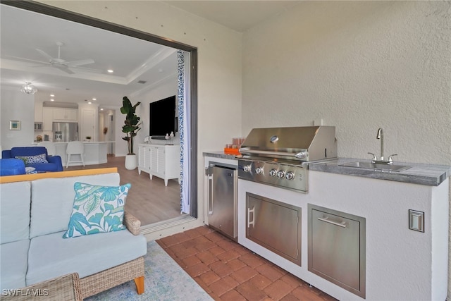 kitchen featuring a tray ceiling, stainless steel appliances, a ceiling fan, white cabinets, and a sink