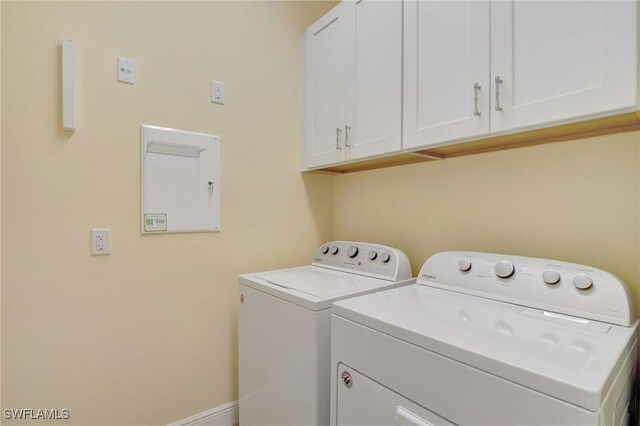 washroom featuring cabinet space, baseboards, and washer and clothes dryer