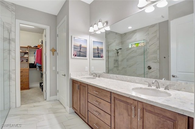 bathroom featuring marble finish floor, a spacious closet, a walk in shower, and a sink