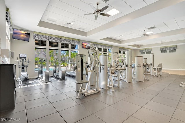 workout area featuring a tray ceiling, visible vents, ceiling fan, and baseboards