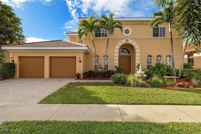 mediterranean / spanish house featuring a garage, decorative driveway, a tiled roof, and stucco siding