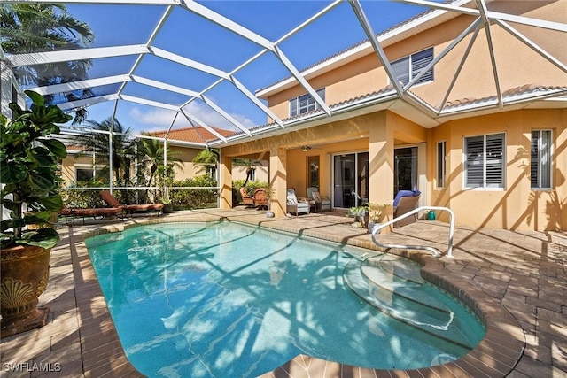 outdoor pool with glass enclosure, ceiling fan, and a patio