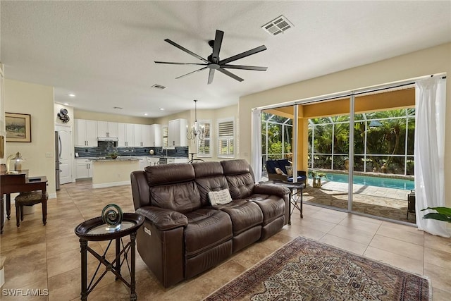8840 Paseo De Valencia St, Fort Myers, FL 33908 - living room with light tile patterned floors, visible vents, a textured ceiling, and ceiling fan with notable chandelier