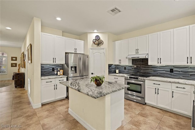 8840 Paseo De Valencia St, Fort Myers, FL 33908 - kitchen with light stone counters, under cabinet range hood, stainless steel appliances, visible vents, and white cabinets