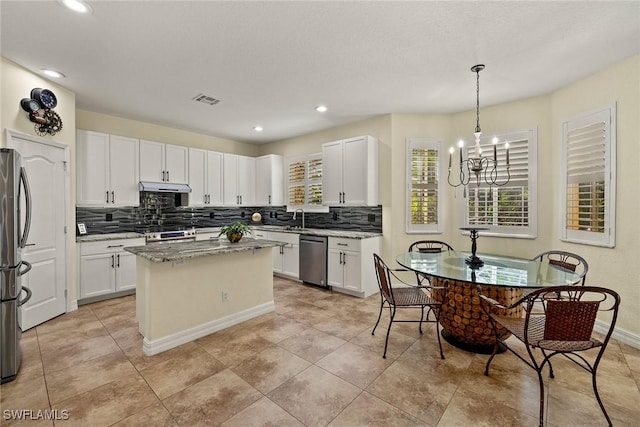 8840 Paseo De Valencia St, Fort Myers, FL 33908 - kitchen featuring under cabinet range hood, stainless steel appliances, a kitchen island, visible vents, and light stone countertops