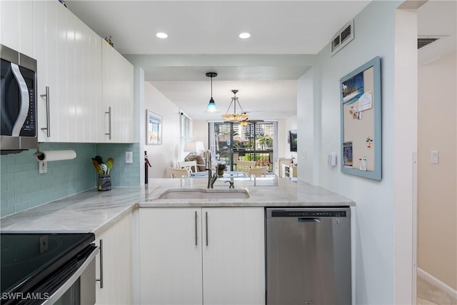 kitchen with tasteful backsplash, stainless steel appliances, light stone countertops, white cabinets, and pendant lighting