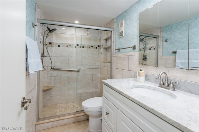 bathroom with toilet, tile walls, vanity, and a shower with door