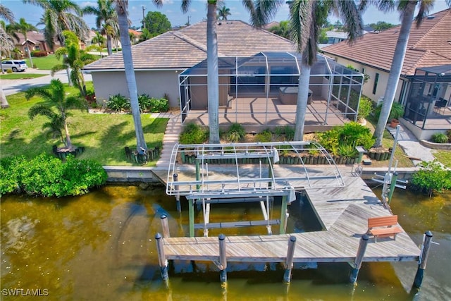 view of dock with glass enclosure, boat lift, a water view, a lawn, and a patio area