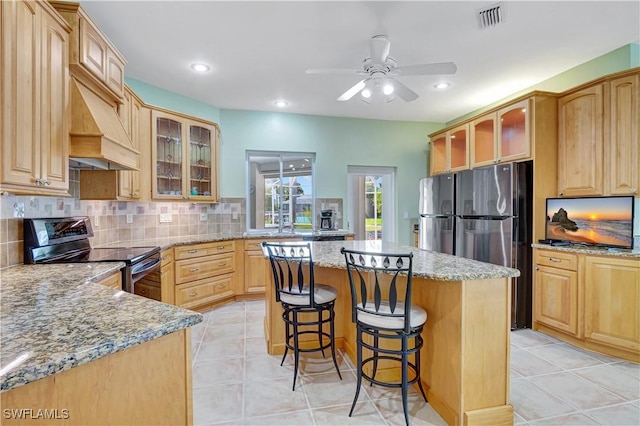 kitchen featuring stainless steel appliances, a center island, visible vents, a kitchen breakfast bar, and decorative backsplash