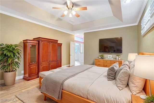 bedroom featuring ceiling fan, wood finish floors, baseboards, ornamental molding, and a tray ceiling