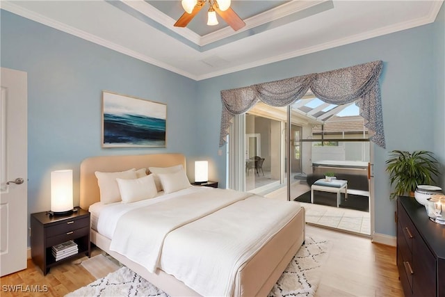 bedroom featuring baseboards, light wood-style floors, access to outside, a tray ceiling, and crown molding