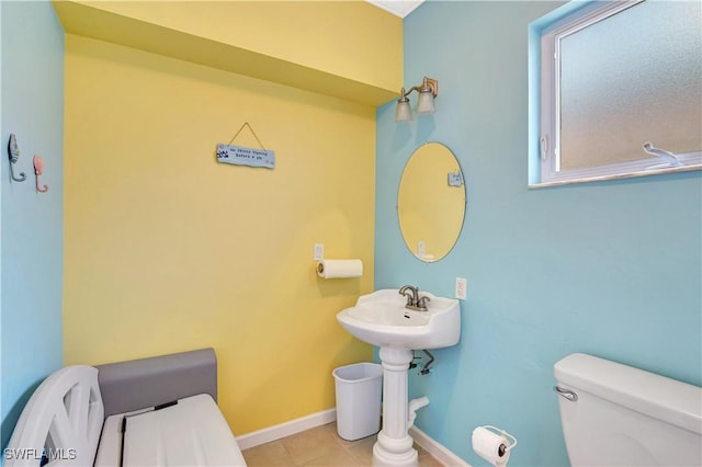 half bath featuring baseboards, toilet, and tile patterned floors