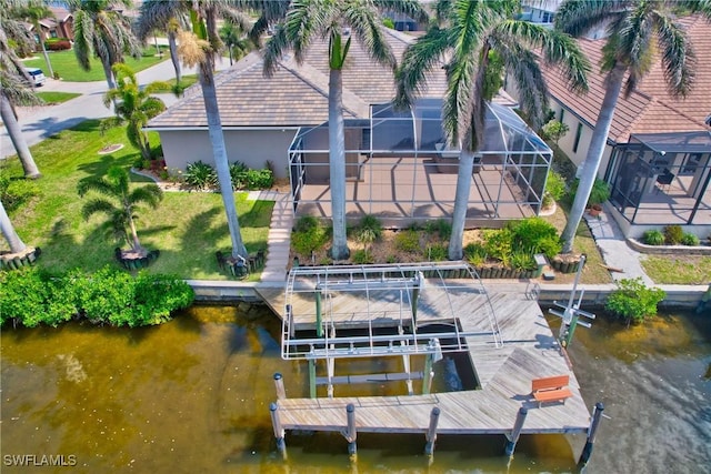 view of dock with boat lift, a lawn, a water view, and a lanai