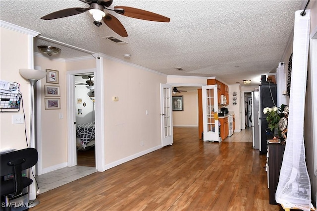 living area with light wood finished floors, visible vents, crown molding, and french doors