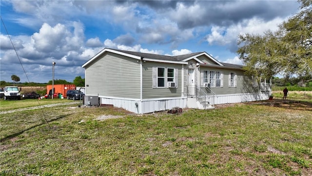 view of side of home with cooling unit and a yard