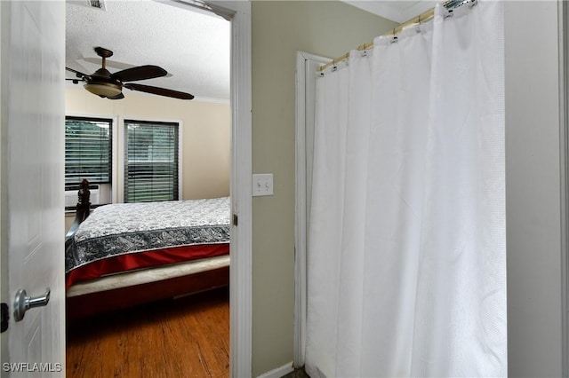 bedroom with crown molding, ceiling fan, a textured ceiling, and wood finished floors