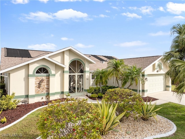 view of front facade with roof with shingles, stucco siding, solar panels, concrete driveway, and an attached garage