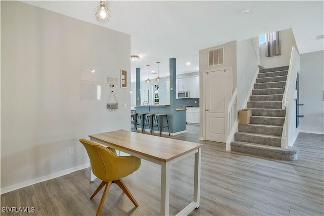 dining room featuring visible vents, baseboards, stairs, and light wood finished floors