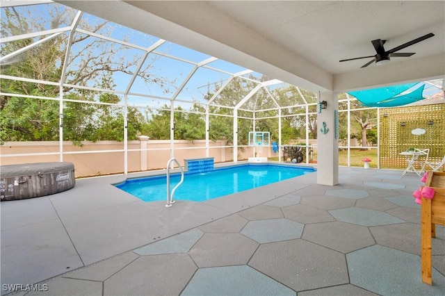 pool with a patio area, glass enclosure, and ceiling fan