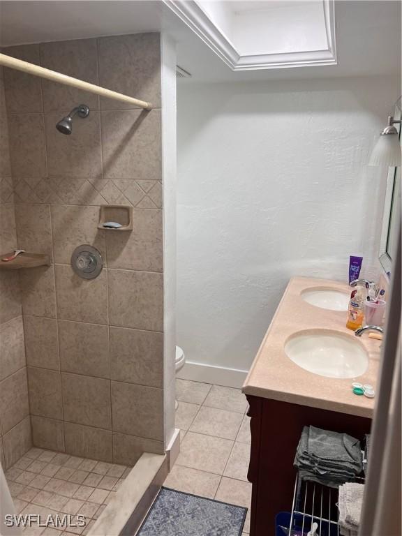 bathroom featuring tile patterned floors, a tile shower, vanity, and toilet