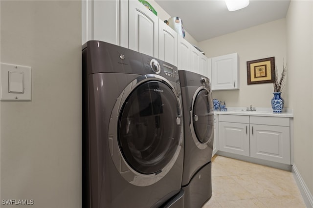 washroom featuring light tile patterned floors, cabinet space, a sink, separate washer and dryer, and baseboards