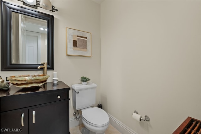 half bath with baseboards, vanity, and toilet