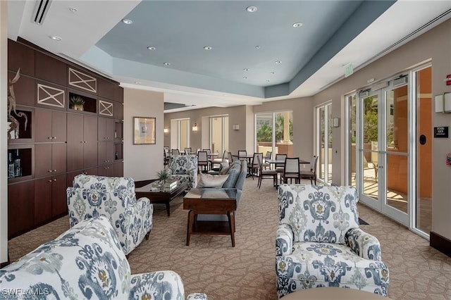 living area featuring recessed lighting, a raised ceiling, visible vents, and light colored carpet