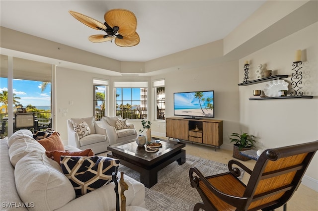 living area with a wealth of natural light, ceiling fan, and baseboards