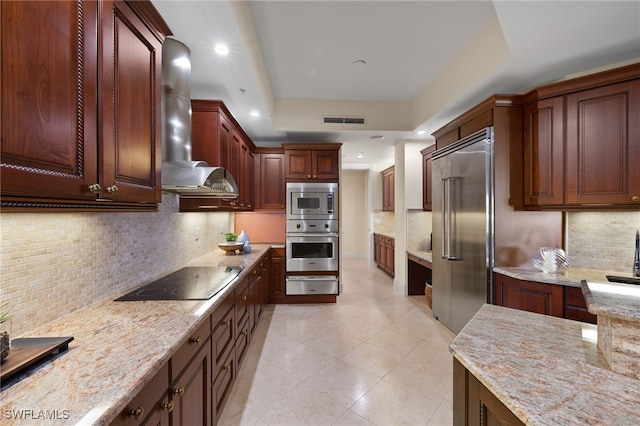 kitchen with light stone counters, a warming drawer, visible vents, wall chimney range hood, and built in appliances