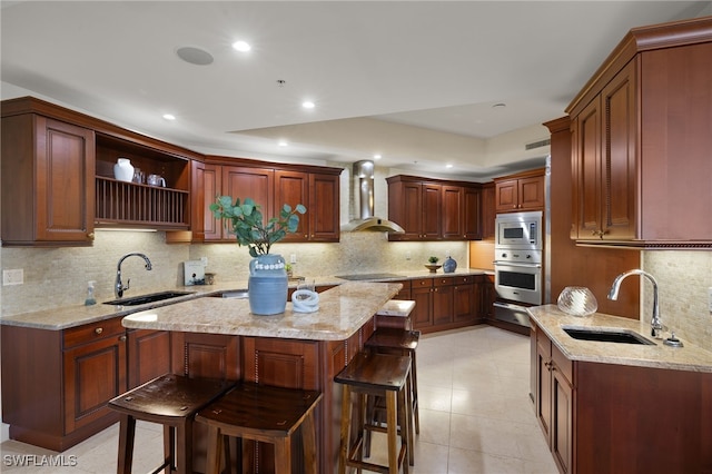 kitchen featuring stainless steel appliances, a breakfast bar, a sink, and wall chimney range hood