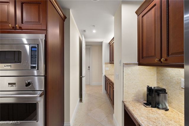 kitchen with light tile patterned flooring, stainless steel appliances, visible vents, backsplash, and light stone countertops