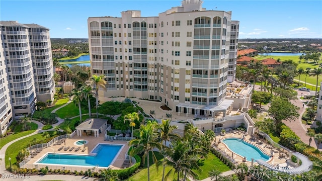 view of building exterior with a water view, a community pool, and fence