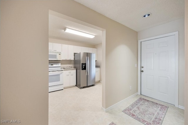 kitchen featuring white appliances, a textured ceiling, and white cabinets