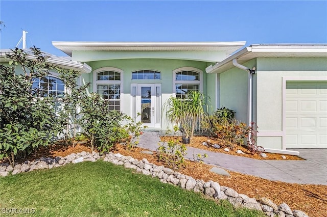 view of front of home with a garage, a front yard, and stucco siding