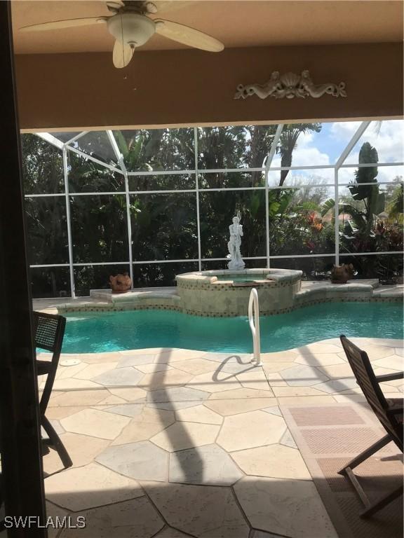 view of swimming pool with a pool with connected hot tub, a patio area, a lanai, and a ceiling fan