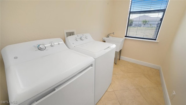 washroom with sink, washing machine and dryer, and light tile patterned floors