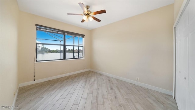 unfurnished room featuring ceiling fan, a water view, and light hardwood / wood-style flooring