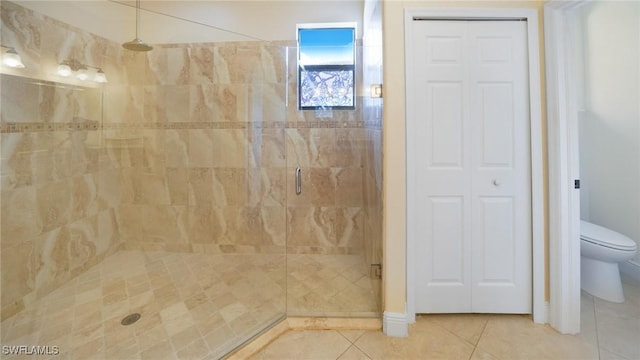 bathroom with tile patterned floors, toilet, and a shower with door